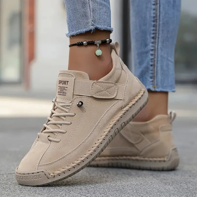 Beige suede lace-up trainers with woven trim and textured rubber sole worn outdoors