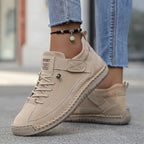 Beige suede lace-up trainers with woven trim and textured rubber sole worn outdoors