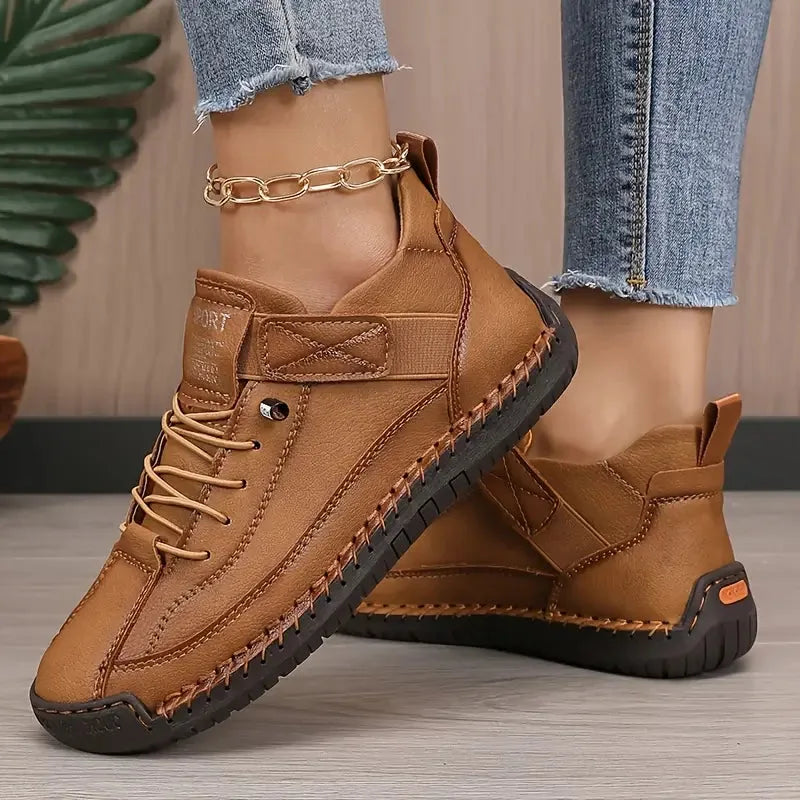 Tan brown leather trainers with hand-stitched panels and ridged non-slip sole shown from the side