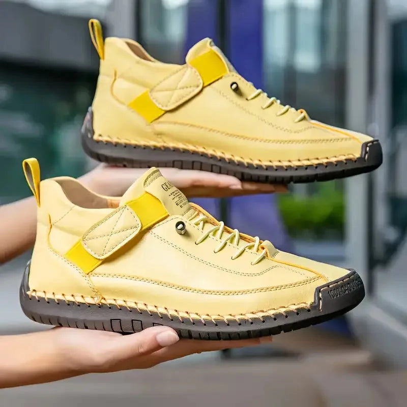Pair of pale yellow leather trainers with quilted strap detail displayed side by side
