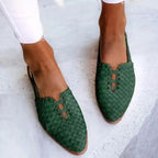 Dark green woven leather flats with pointed toe, slingback-style heel and lace detailing, worn on light stone tiles