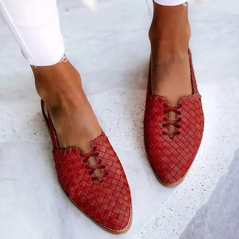Red woven leather flats photographed from the front, showing the braided texture and pointed toe shape