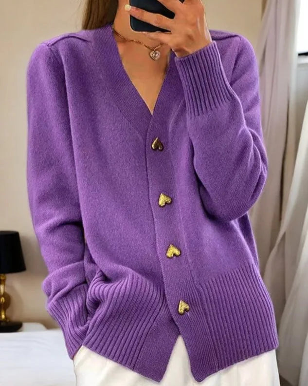 Purple knitted cardigan with gold heart buttons and ribbed hem, paired with a gold heart necklace
