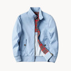 Front flat lay of navy blue jacket showing flap pockets, ribbed hem and tartan-lined interior
