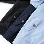 Side-by-side cuff detail of black, navy and sky blue jacket versions showing flap pocket and button