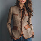 Front view of a tweed jacket with tan faux leather trim on the collar, cuffs and pocket flaps, worn over a brown shirt
