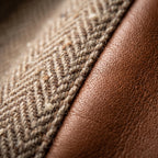Close-up of the herringbone tweed fabric next to the smooth tan faux leather trim, showing texture contrast