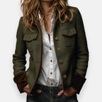 Woman modelling an olive herringbone tweed jacket with brown contrast cuffs over a white shirt