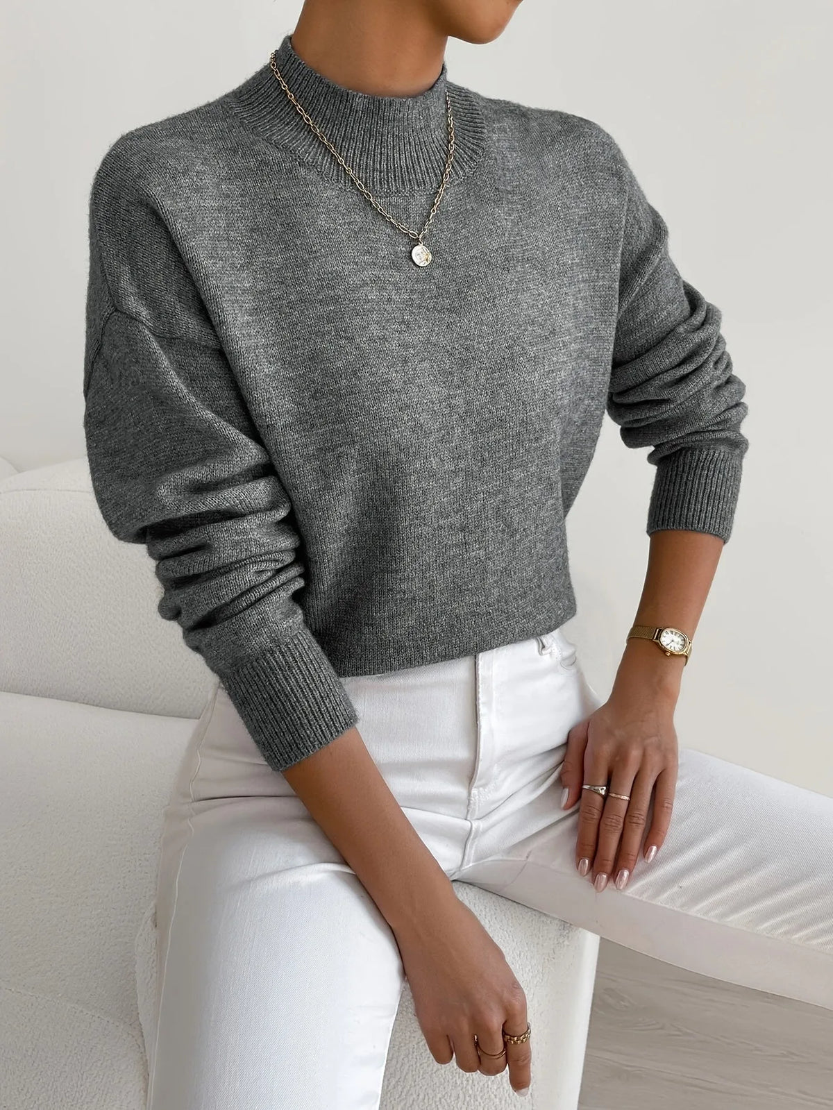 Side view of high neck jumper showing drop shoulder seam and ribbed cuff on the sleeve.