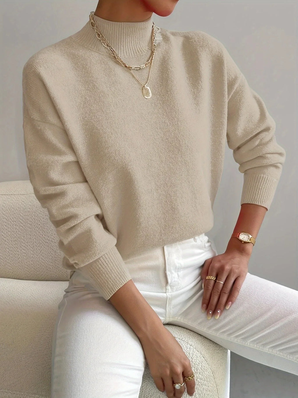 Beige high neck jumper with ribbed mock collar, soft brushed knit visible in close-up detail.