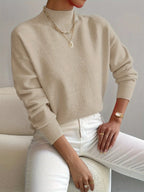Beige high neck jumper with ribbed mock collar, soft brushed knit visible in close-up detail.