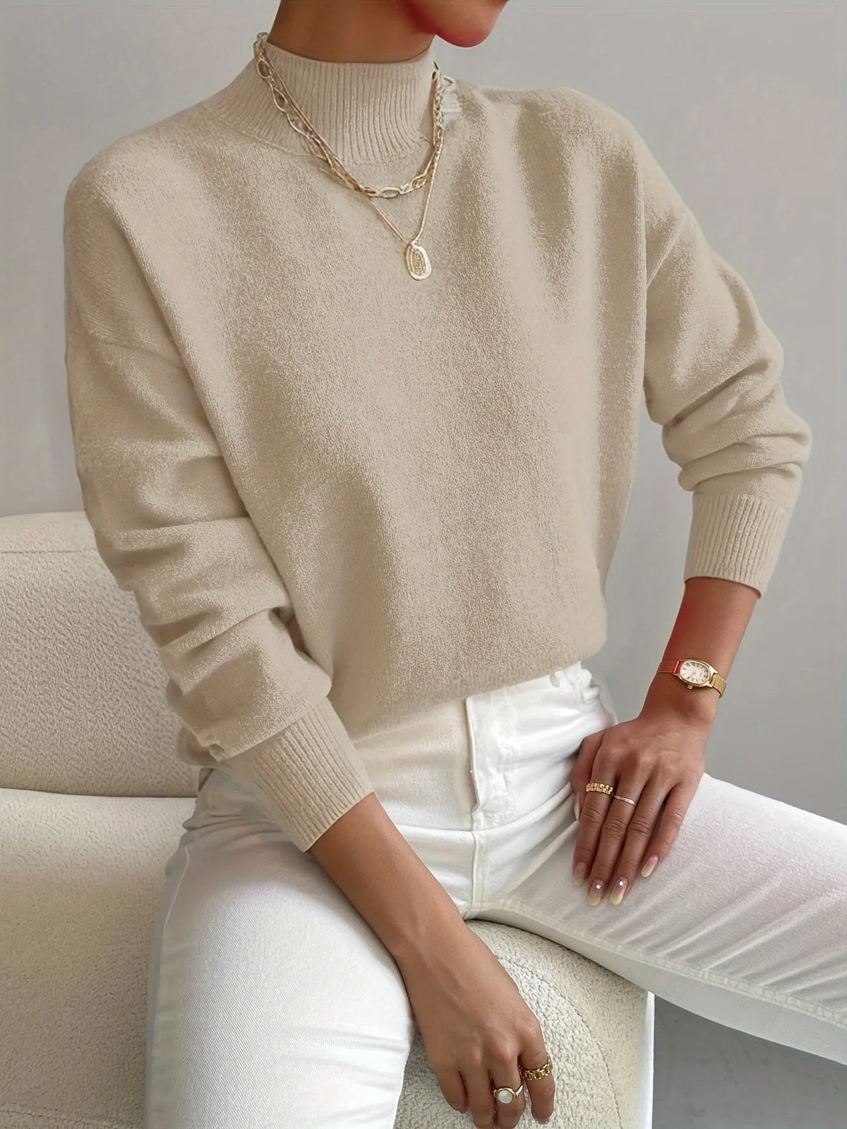 Beige high neck jumper with ribbed mock collar, soft brushed knit visible in close-up detail.