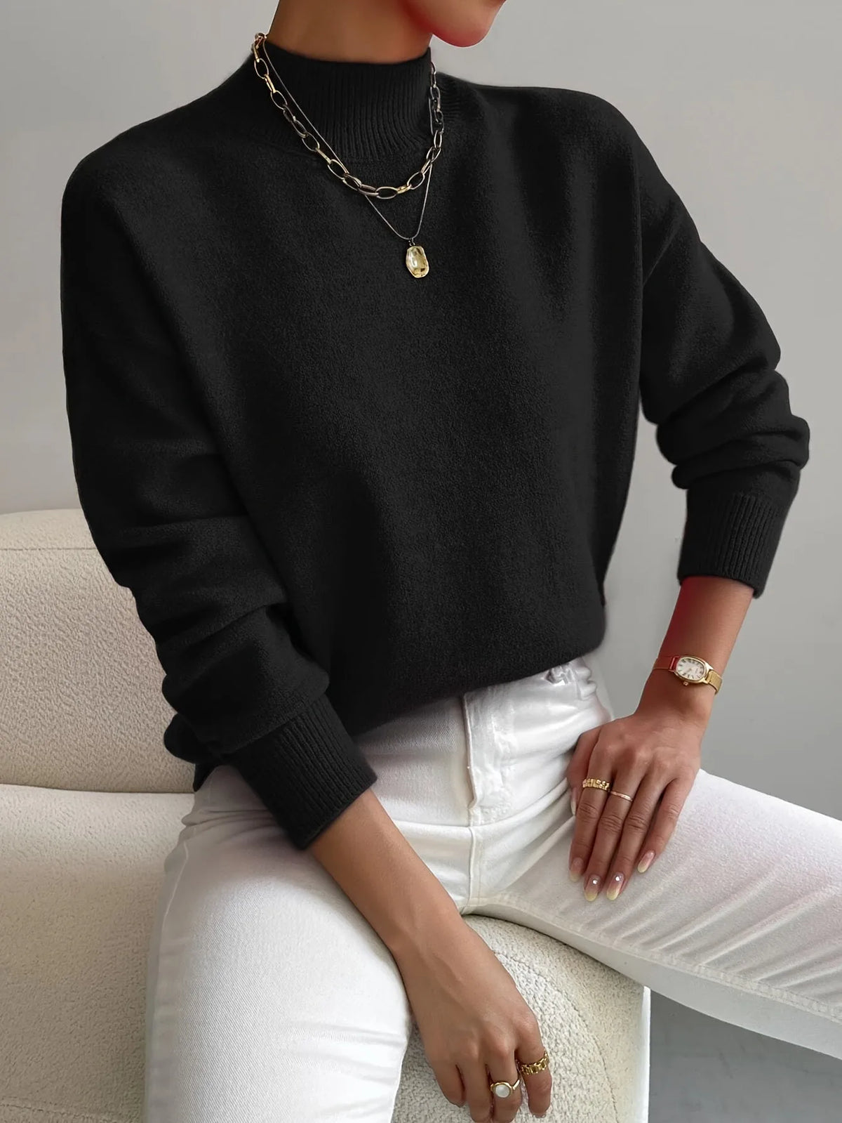 Black high neck jumper with mock neck and ribbed cuffs, styled with layered gold and silver necklaces.