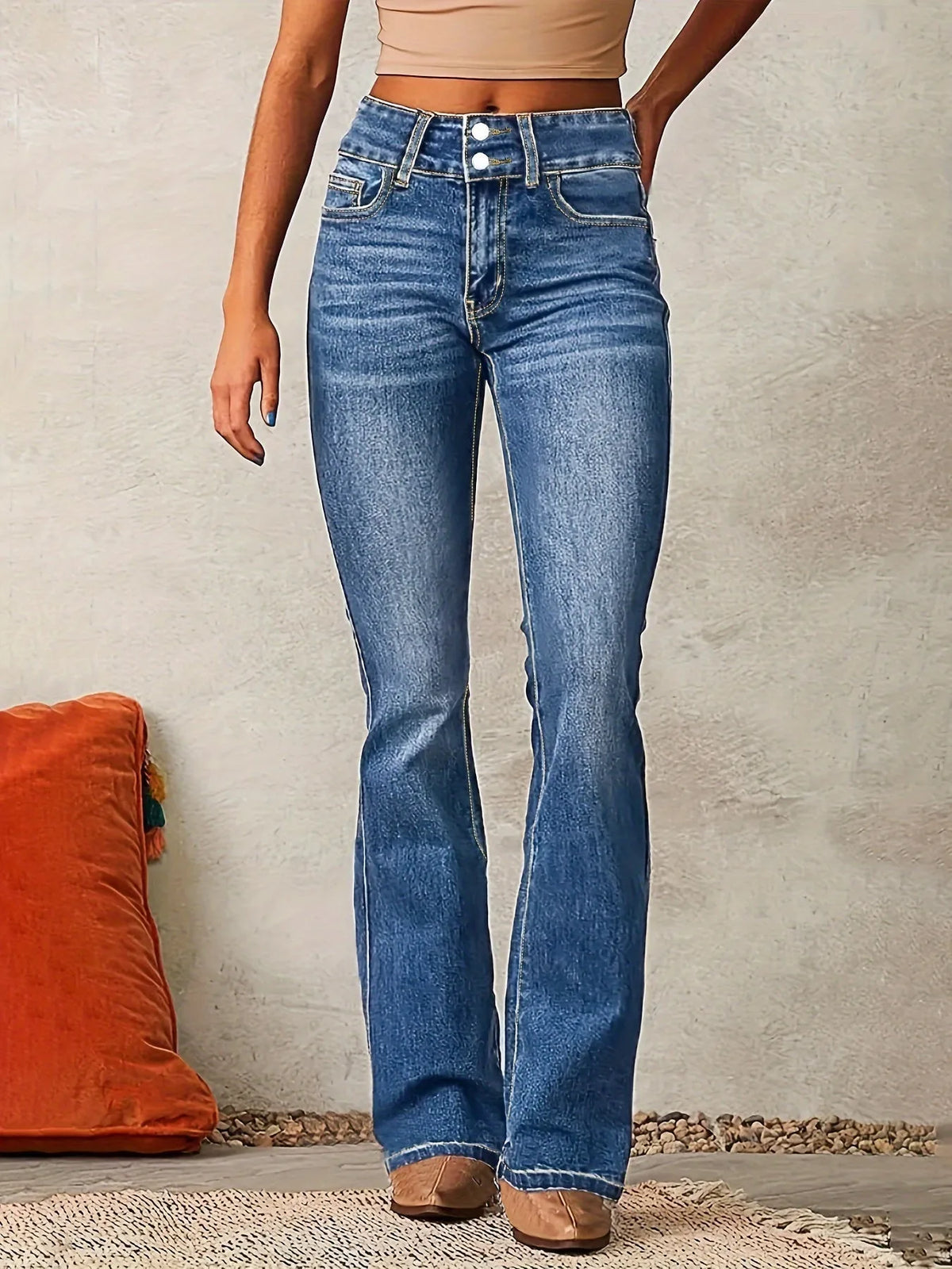 Front view of mid-blue wash flared jeans with high waist, double button fastening and topstitched pockets
