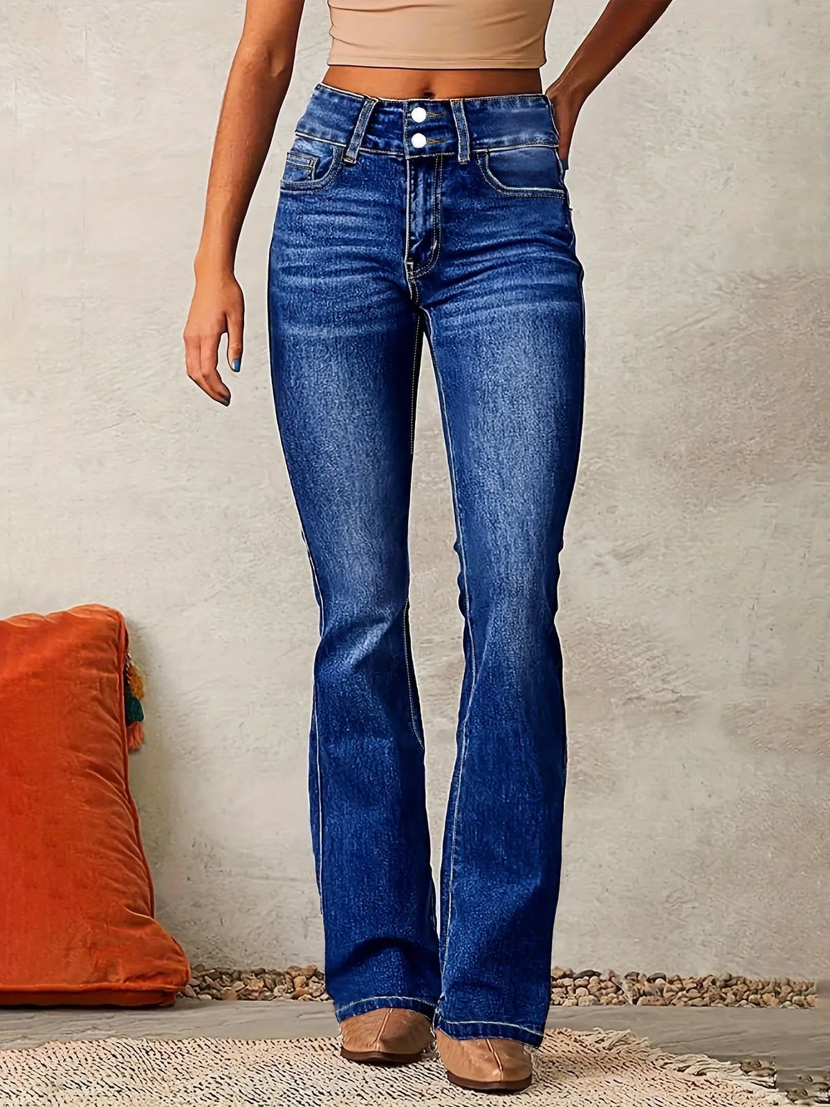Close-up front view of dark blue denim flared jeans showing high waist, button fly and contrast stitching