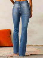 Back view of mid-blue flared jeans showing high waist, curved yoke and topstitched patch pockets