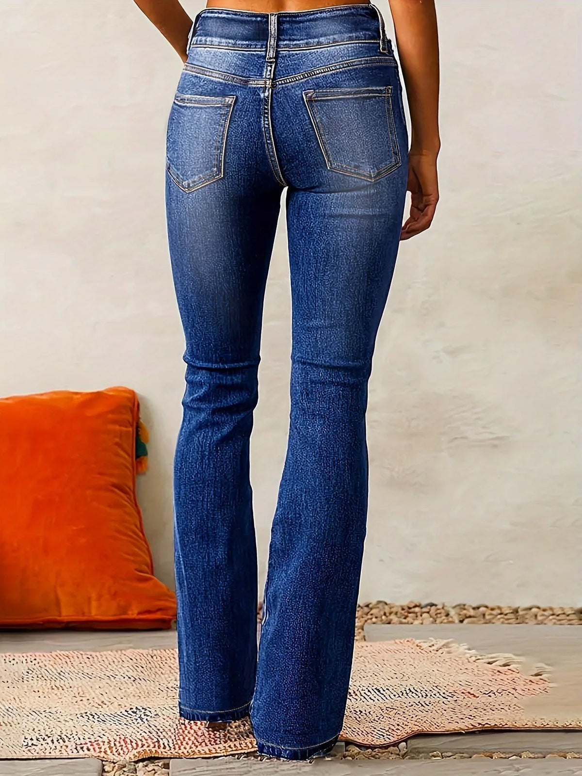 Back view of mid-blue flared jeans highlighting the fitted hip, seat shaping and flared hem