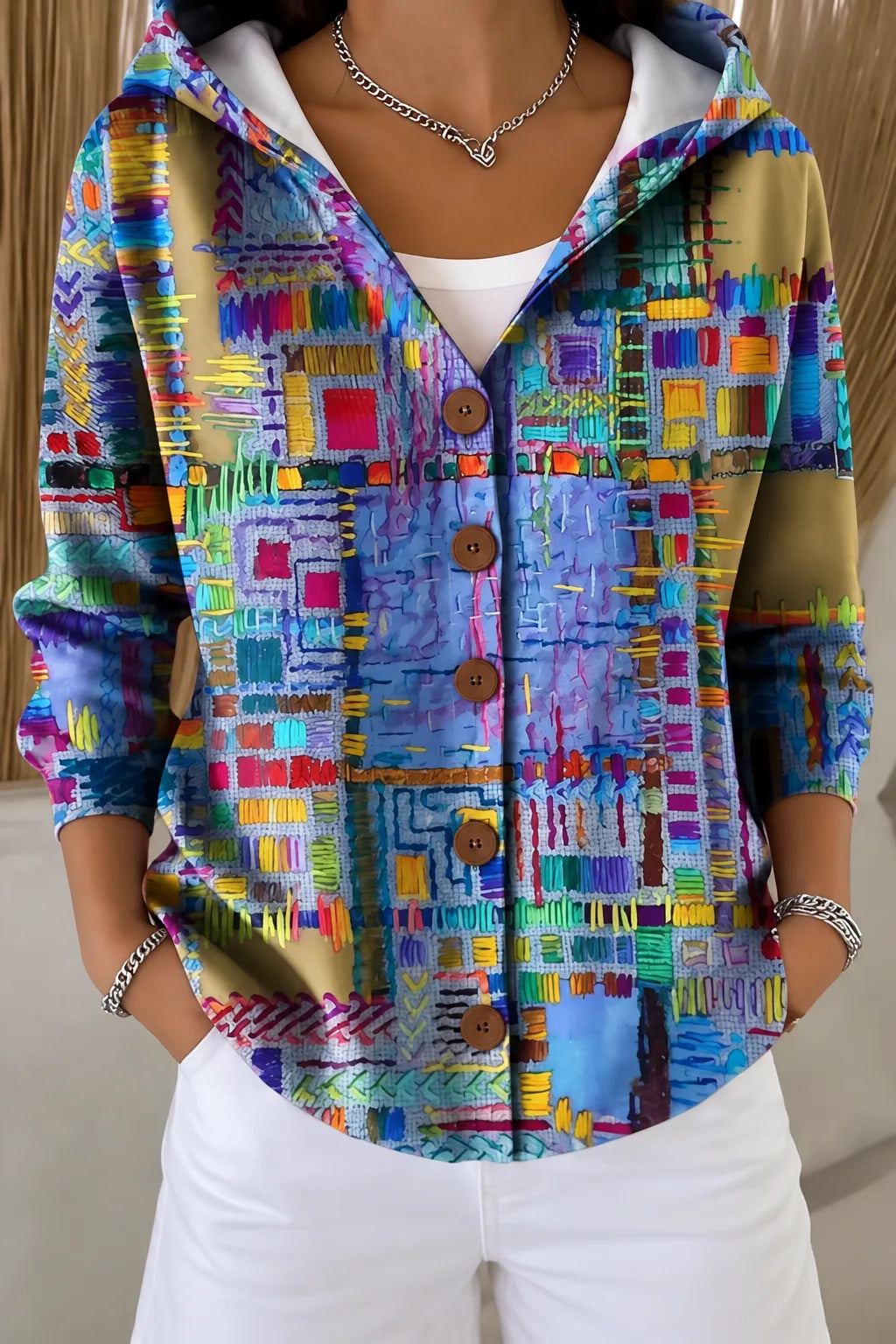 Model wears a button-front hooded jacket with a colourful abstract patchwork print in blue, purple and yellow tones