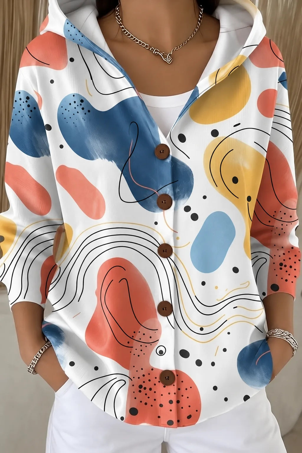 White hooded button jacket featuring bold abstract shapes in terracotta, mustard and navy with fine line art detail