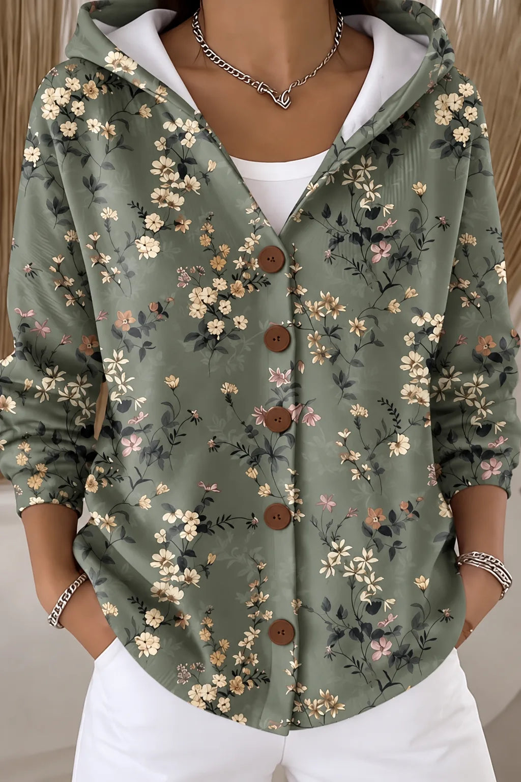 Sage green hooded cardigan-style jacket covered in a delicate wildflower and leaf print with brown buttons