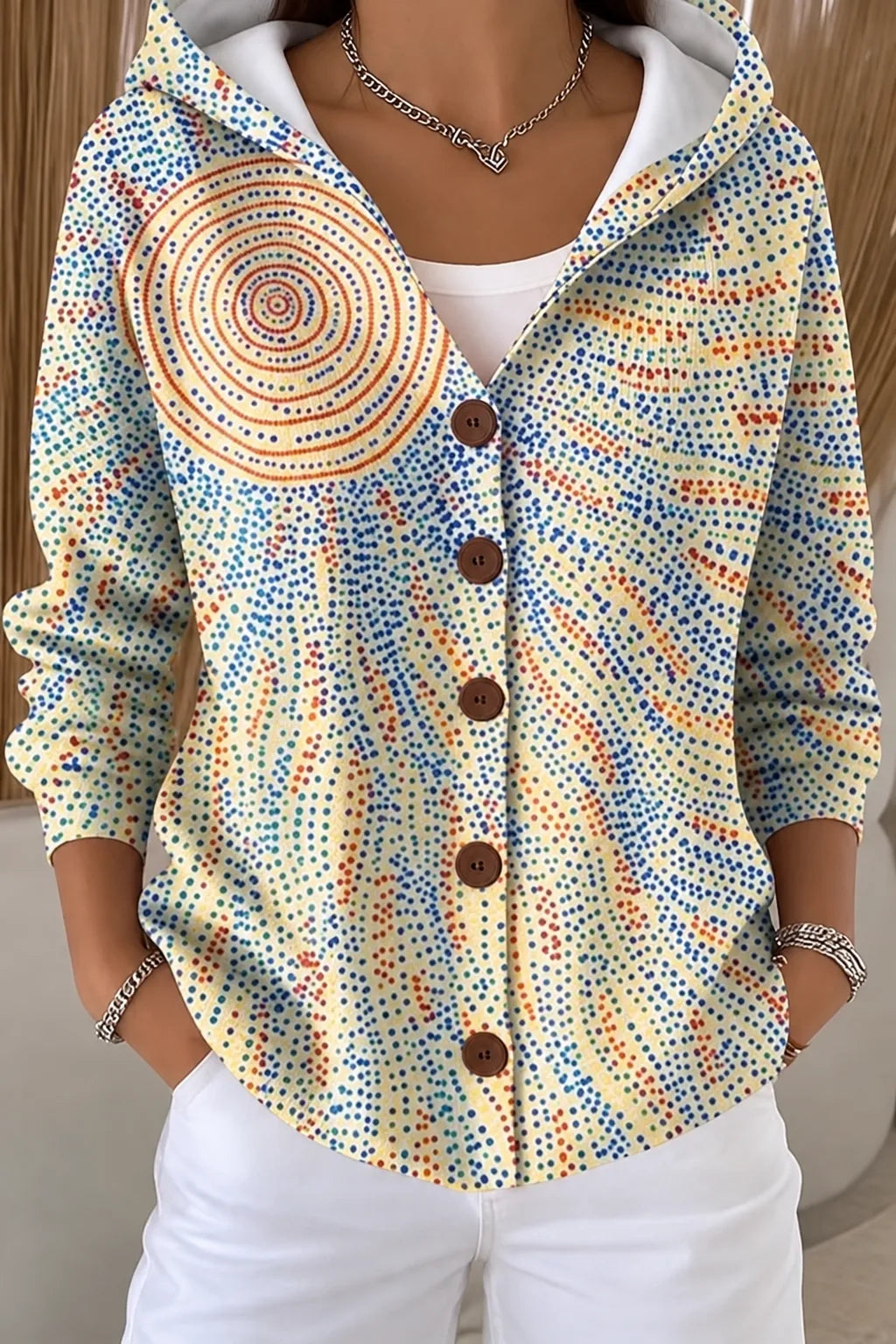 Pale yellow hooded jacket with a fine multicolour dotted pattern and a circular sunburst motif on the shoulder