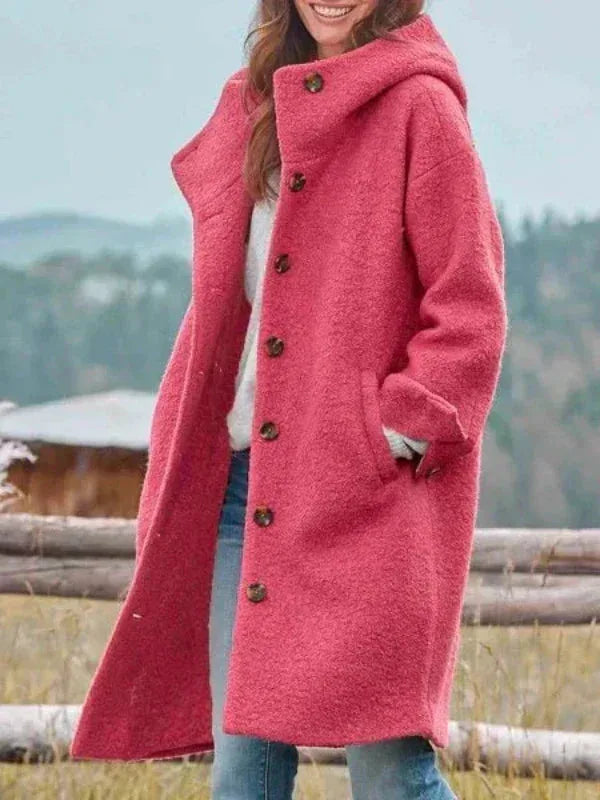 Side view of a woman wearing a pink hooded longline wool coat with button front and side pockets