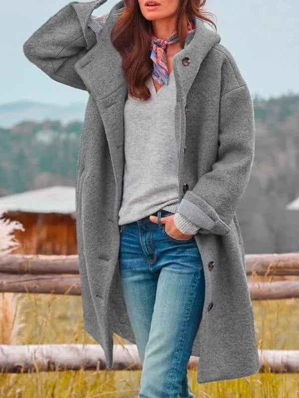 Grey hooded longline wool coat with striped cuff detail, styled with jeans and scarf