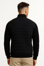 Back view of the black quilted jacket showing the knitted sleeves and horizontal quilted panelling across the shoulders