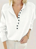 Close-up of a white knit jumper showing the button-front V-neck and small folded collar detail