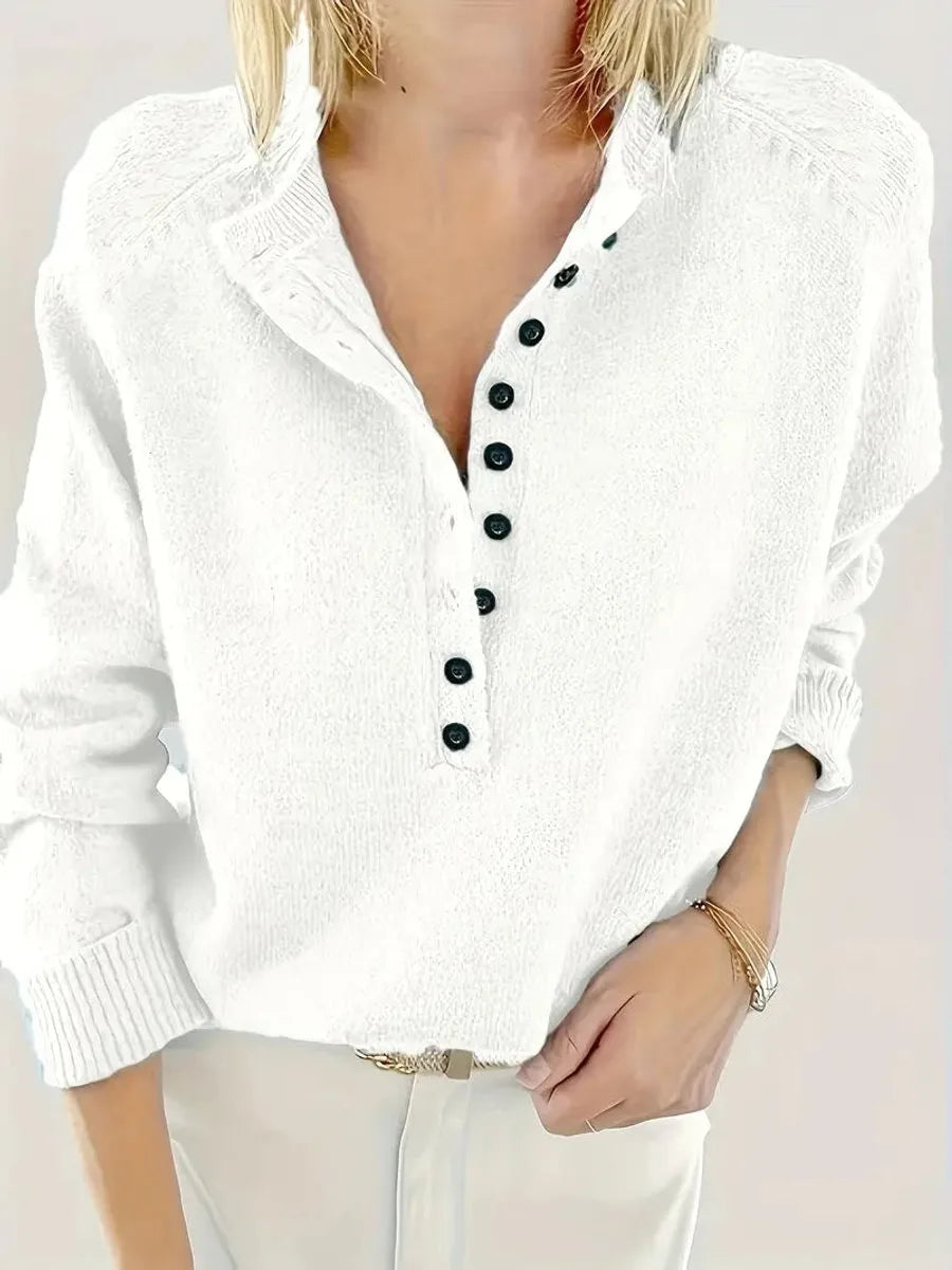 Close-up of a white knit jumper showing the button-front V-neck and small folded collar detail