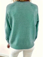 Back view of an emerald green knit jumper showing the relaxed fit and ribbed hem
