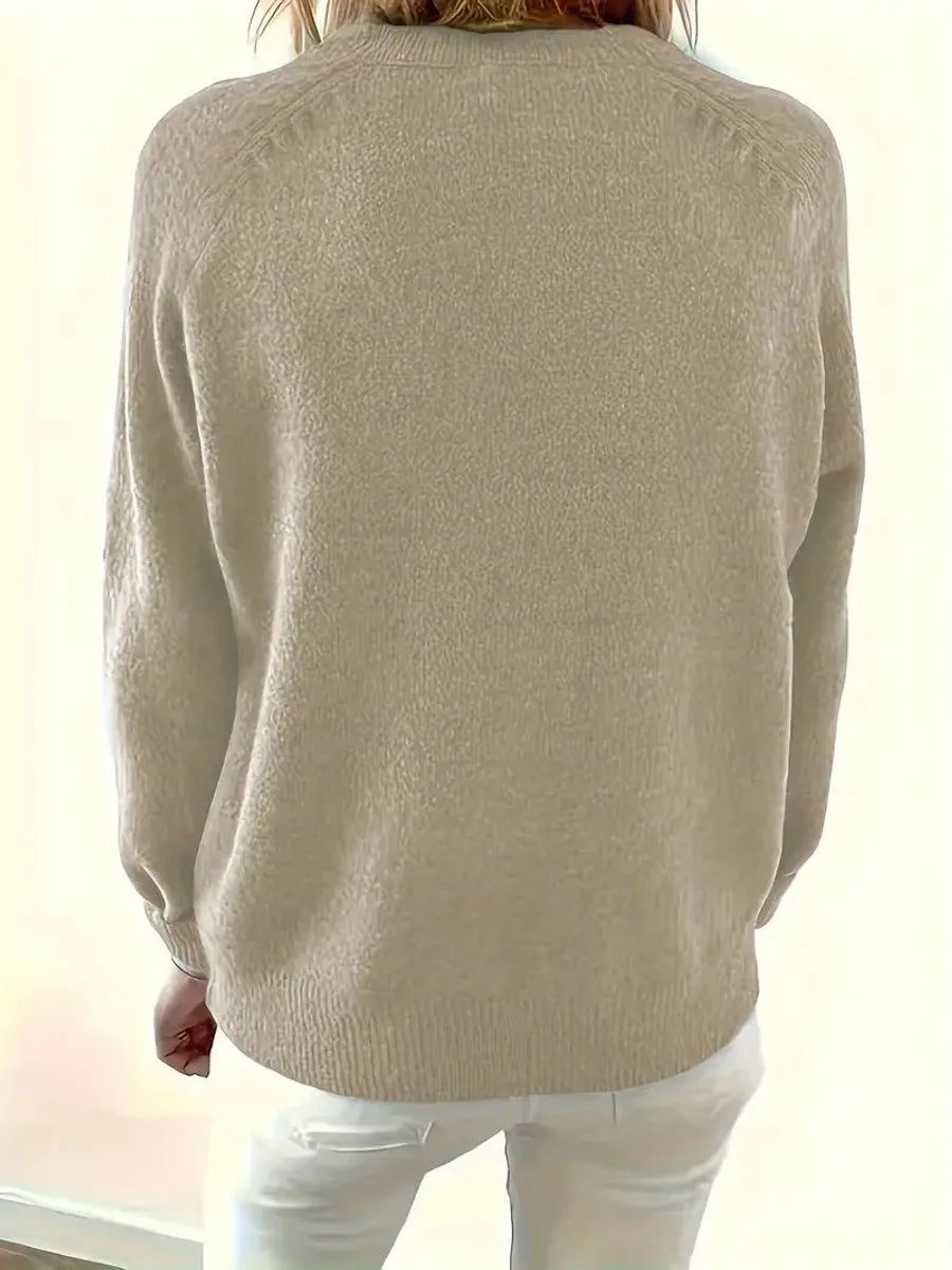 Back view of a beige knit jumper showing the loose fit and ribbed waist hem