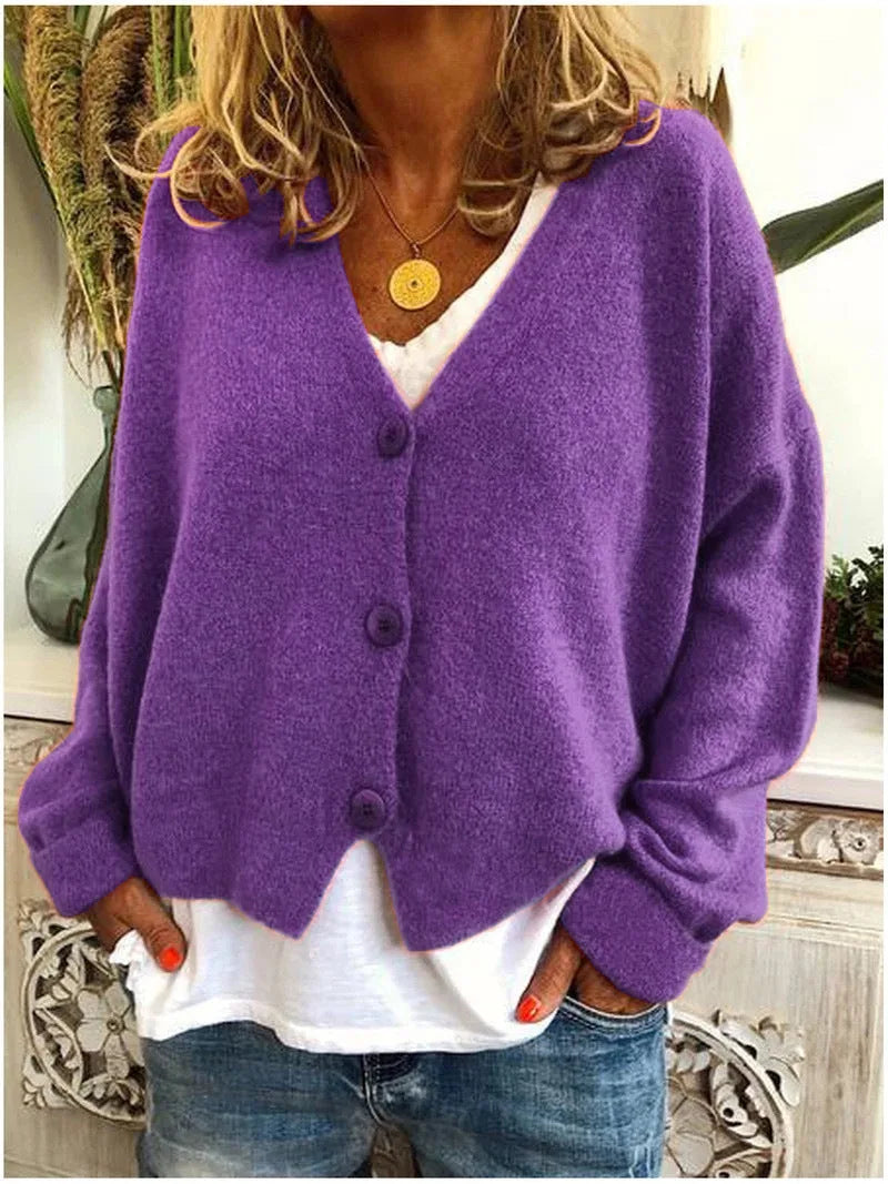 Purple knitted V-neck cardigan with three front buttons, shown worn with a white top and jeans