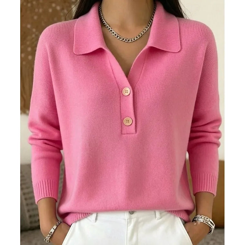 Pink knitted collared jumper with button placket, paired with a layered silver chain necklace and white trousers.