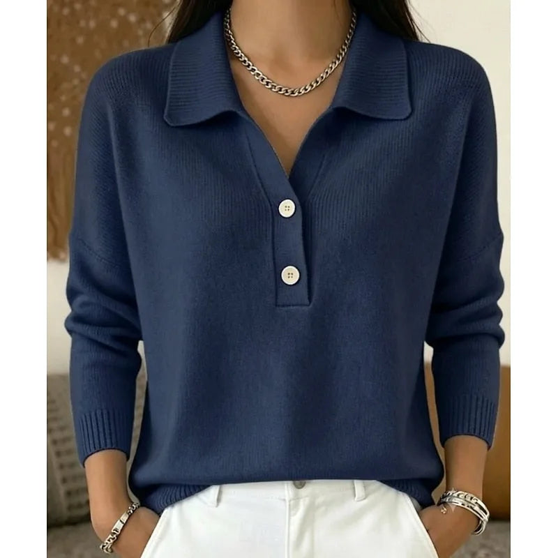 Dark navy blue knitted polo jumper with ribbed collar and cuffs, paired with white trousers and a chunky necklace.
