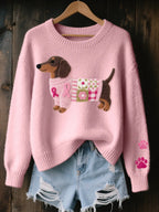 Pink knitted jumper on a hanger with a felt dachshund motif wearing a pink ribbon patchwork sweater and paw prints on the sleeve
