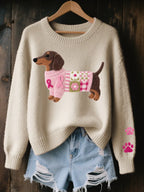 Beige knitted jumper with the dachshund motif in a pink ribbon patchwork sweater, hung against a dark wood backdrop