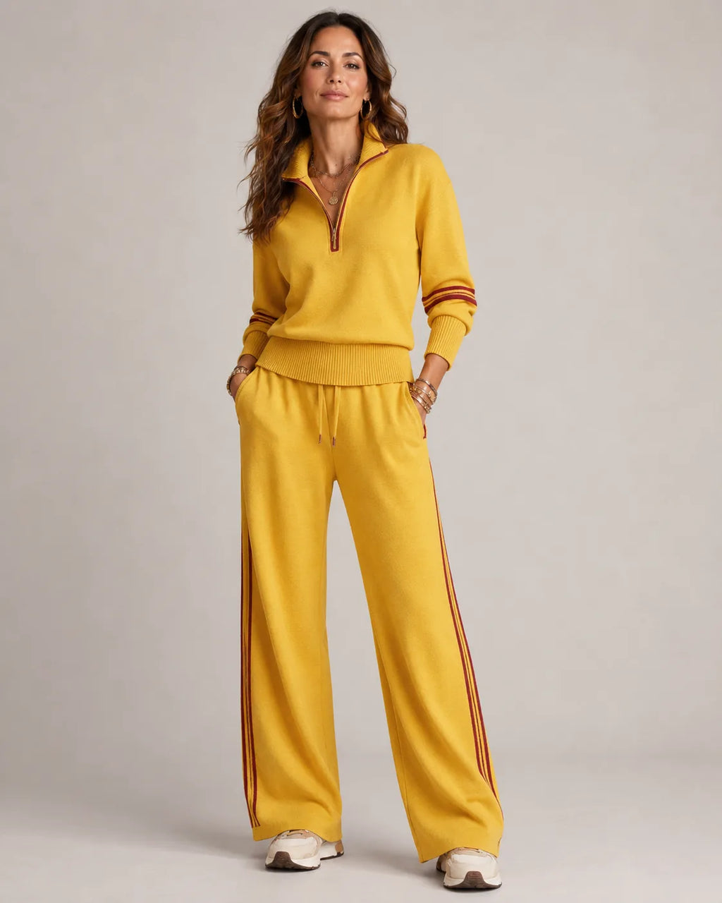 Mustard yellow quarter-zip jumper and wide-leg trousers with burgundy stripe trim, styled with gold jewellery