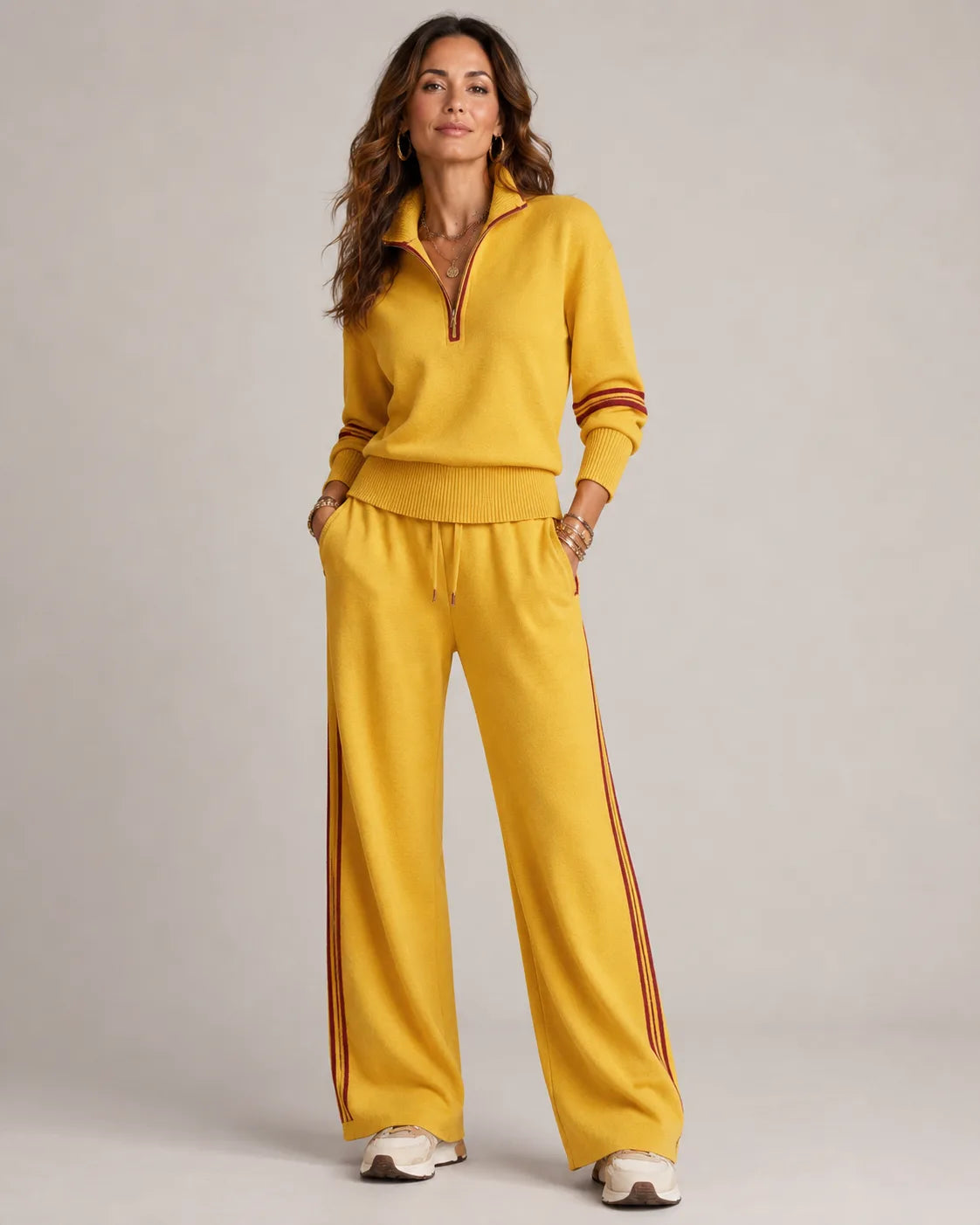 Mustard yellow quarter-zip jumper and wide-leg trousers with burgundy stripe trim, styled with gold jewellery