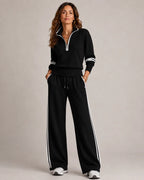 Black quarter-zip jumper and wide-leg trousers with crisp white stripe trim along the sleeves, waistband and trousers