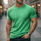 Man wearing a green short-sleeve knitted tee on a city street, textured soft-knit fabric with ribbed crew neckline