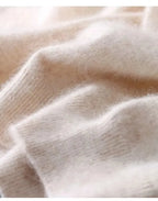 Close-up of beige knit fabric folded to show its soft fluffy texture and ribbed hem detail