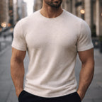 Man wearing an ivory off-white short-sleeve knitted tee with a relaxed fit on a city street