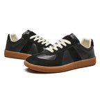 Pair of black leather and suede trainers shown together from an angled front view with gum soles