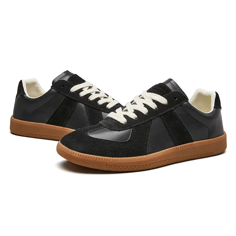 Pair of black leather and suede trainers shown together from an angled front view with gum soles