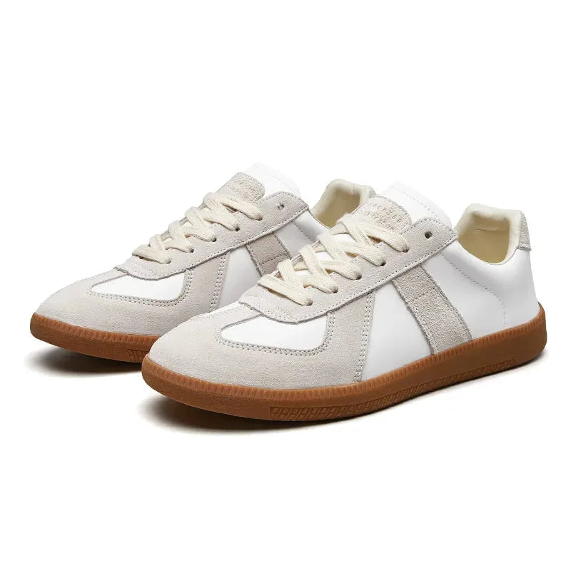 Pair of white and grey suede trainers shown from an angled front view with cream laces and gum soles