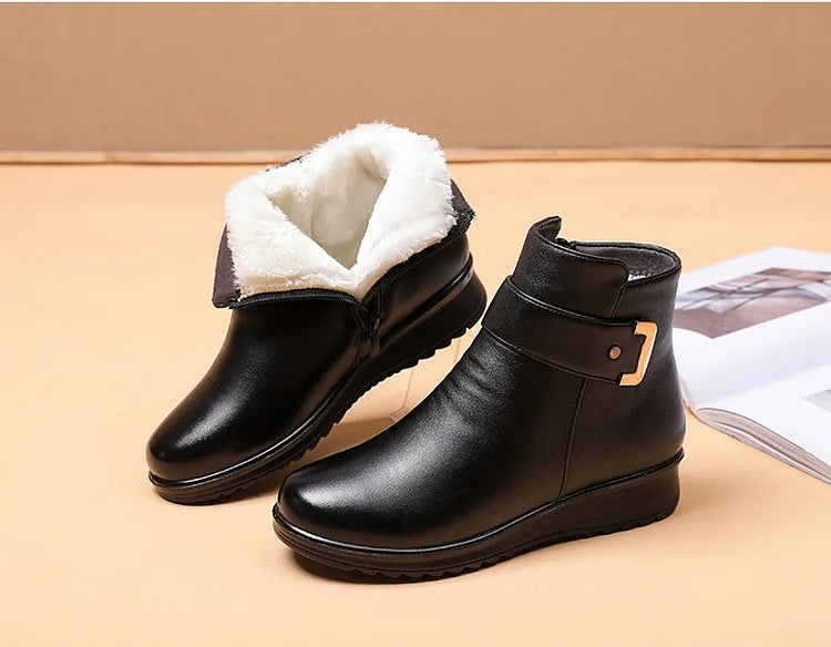 Pair of black leather ankle boots with fold-down shearling cuff, buckle detail and low wedge sole