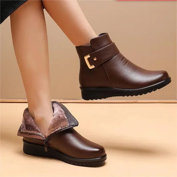 Woman's legs wearing brown leather ankle boots with buckle strap, one boot folded to reveal warm fleece lining