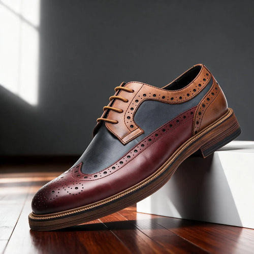 Burgundy, navy and tan wingtip brogue derby shoe shown in side profile with tan laces on a wooden floor