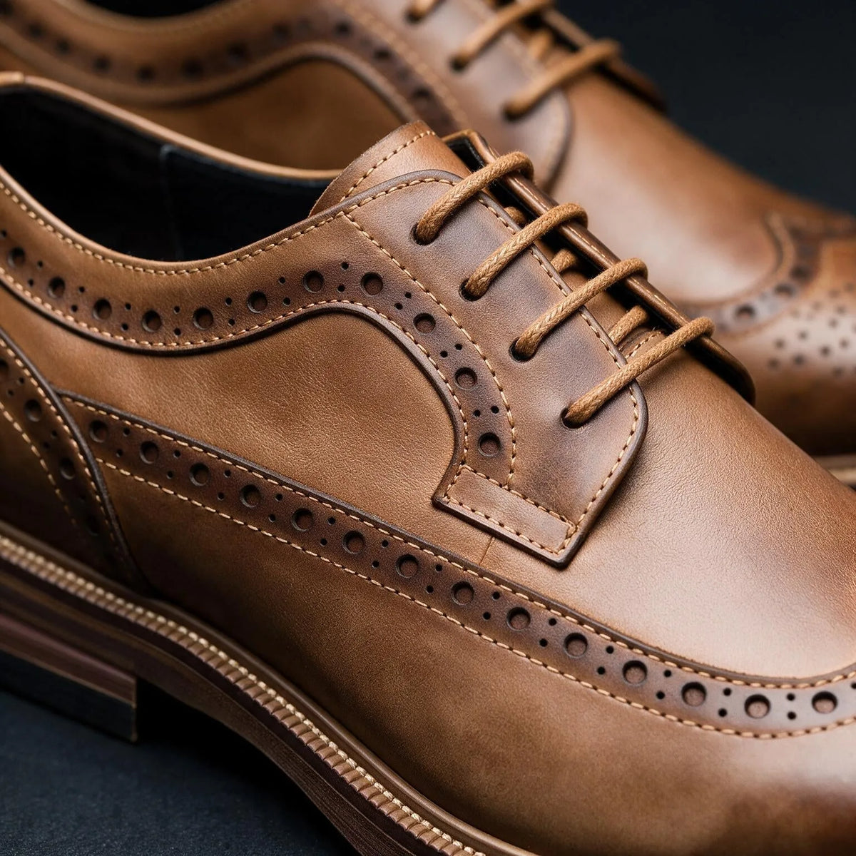 Macro shot of tan brown brogue derby shoes highlighting the waxed laces and pinhole detailing